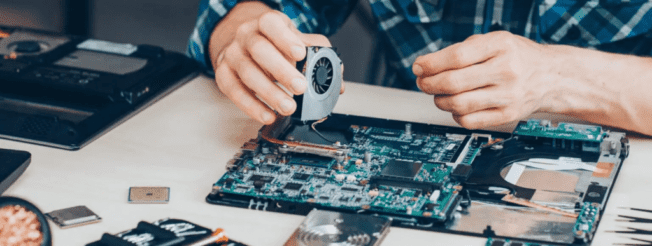 Human hands repairing a laptop motherboard