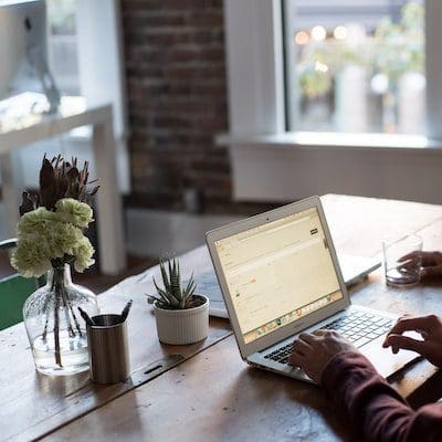 Image of a laptop on a desk with someone working on it.