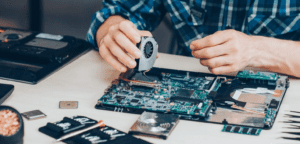 Human hands repairing a laptop motherboard